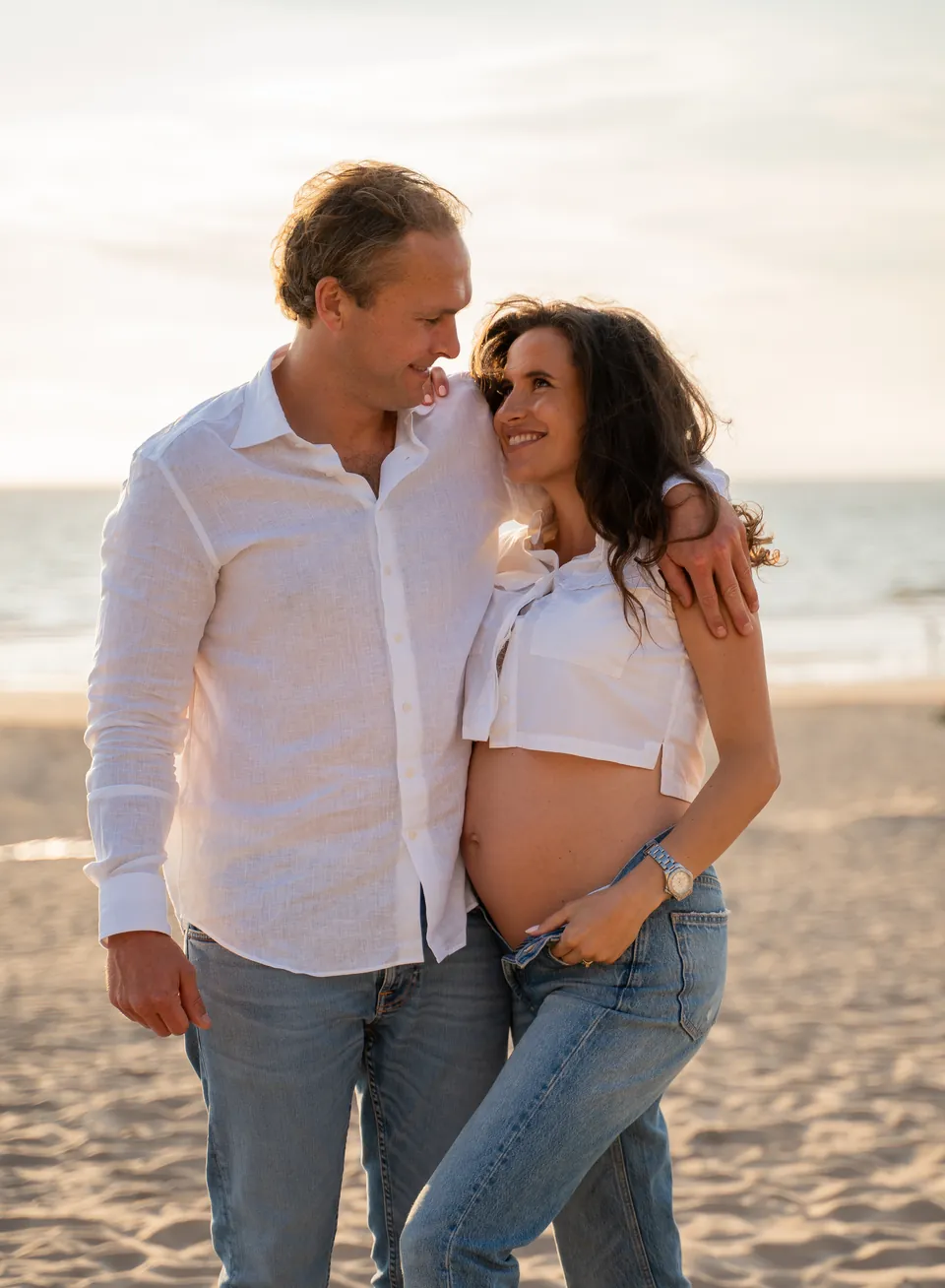 Aanstaande ouders lachen samen op het strand